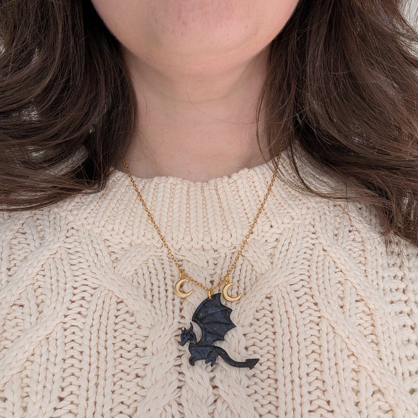 Midnight marble dragon necklace with two gold crescent moon charms worn over a cream sweater