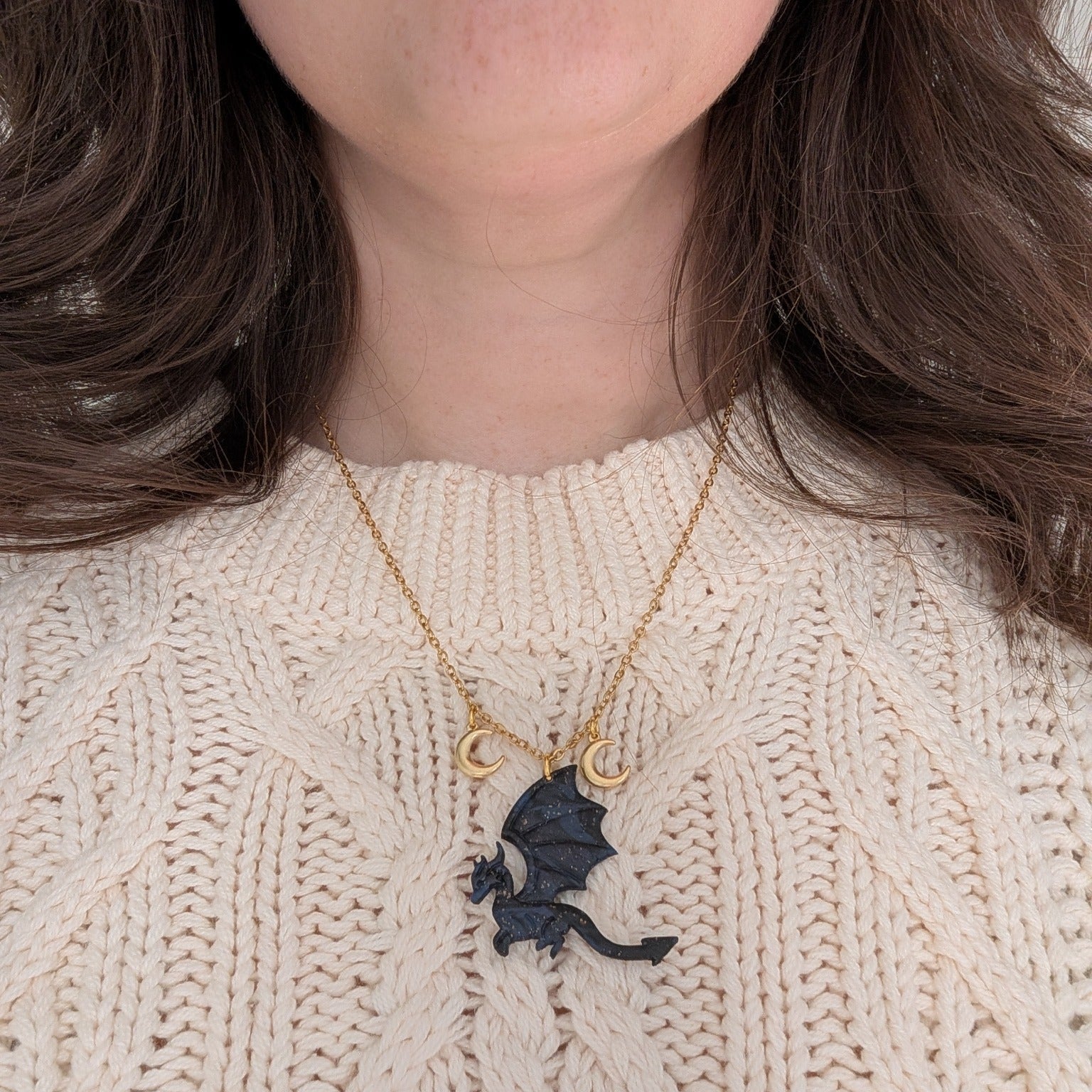 Midnight marble dragon necklace with two gold crescent moon charms worn over a cream sweater