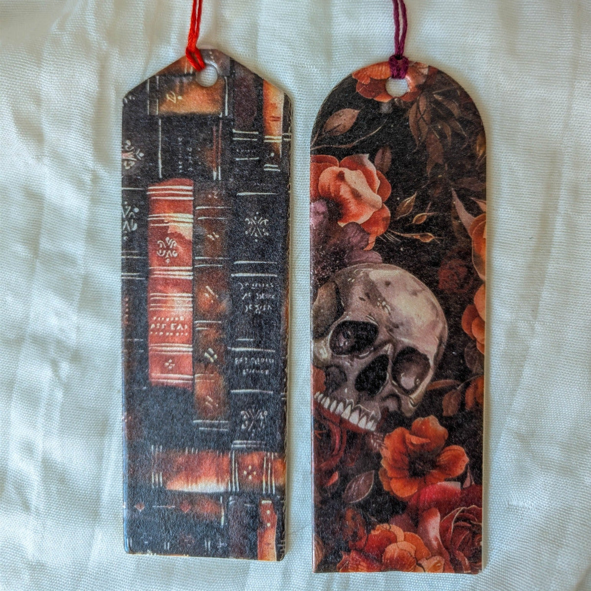Two handmade Halloween bookmarks featuring a dark vintage library and a floral skull with red and purple tassels
