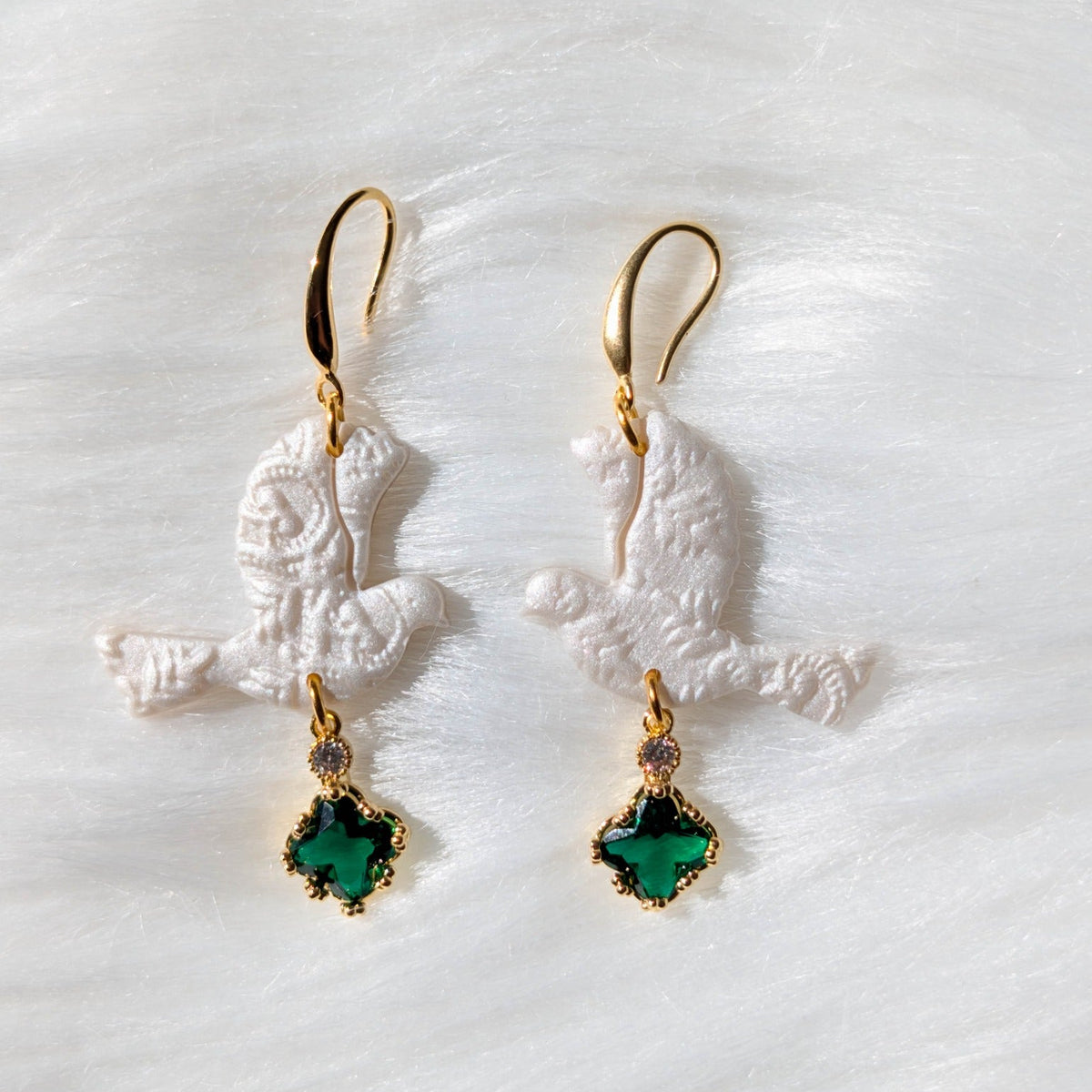Close-up of green lace turtle dove earrings with ornate gold-tone crystal drops