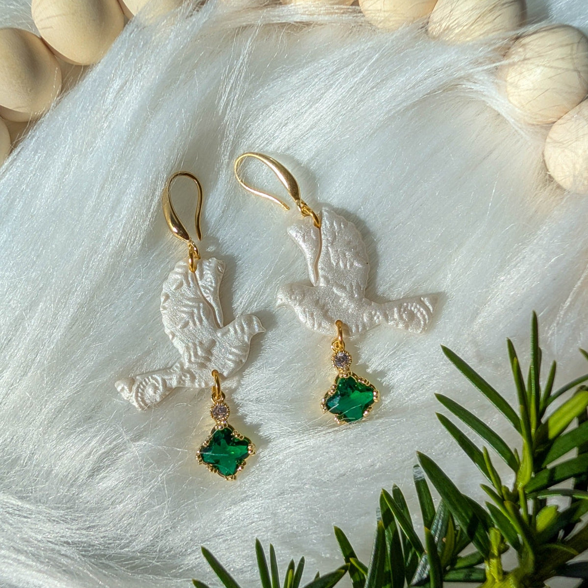 Green lace turtle dove earrings styled with winter greenery and gold-tone details