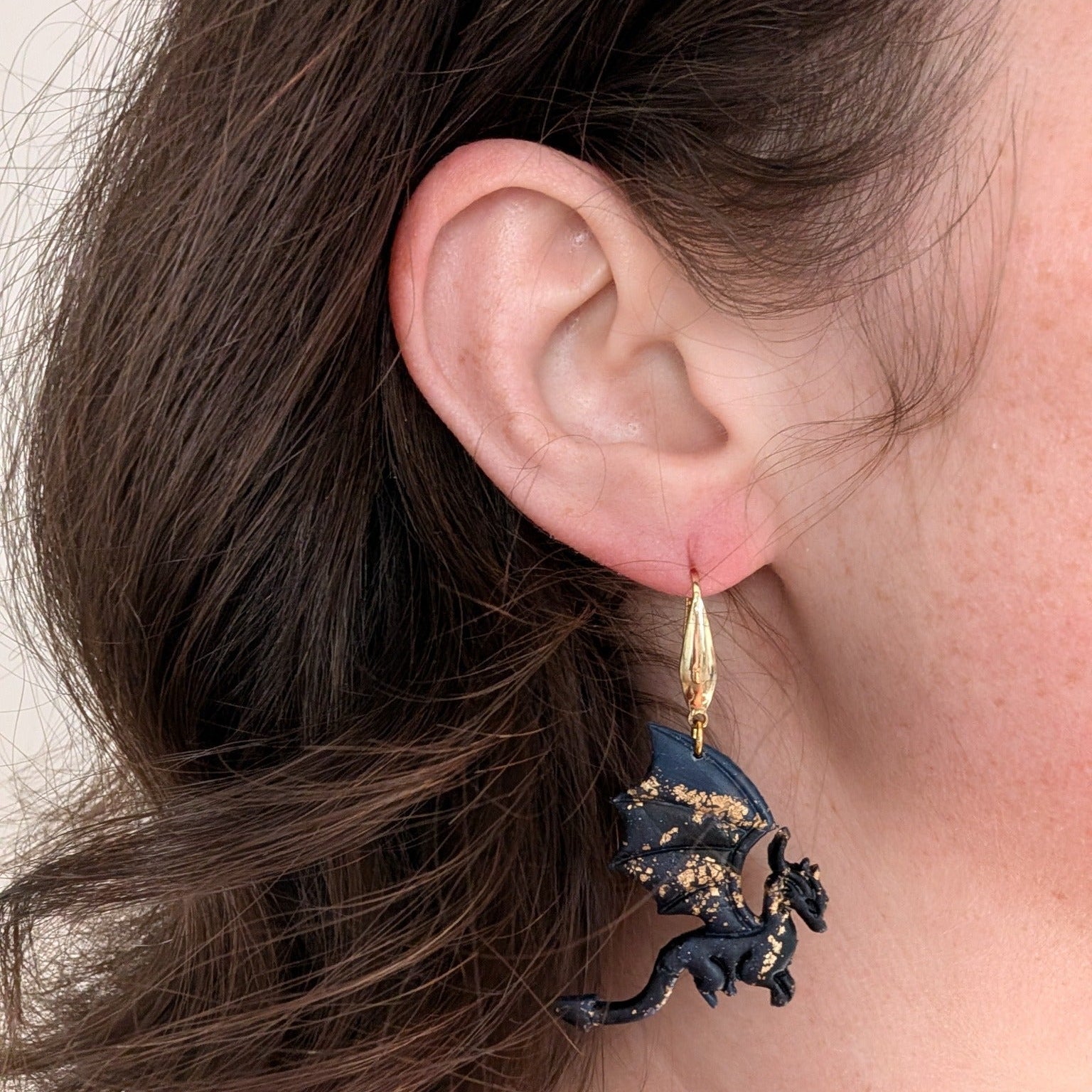 Midnight marble dragon earring with gold accents worn on ear