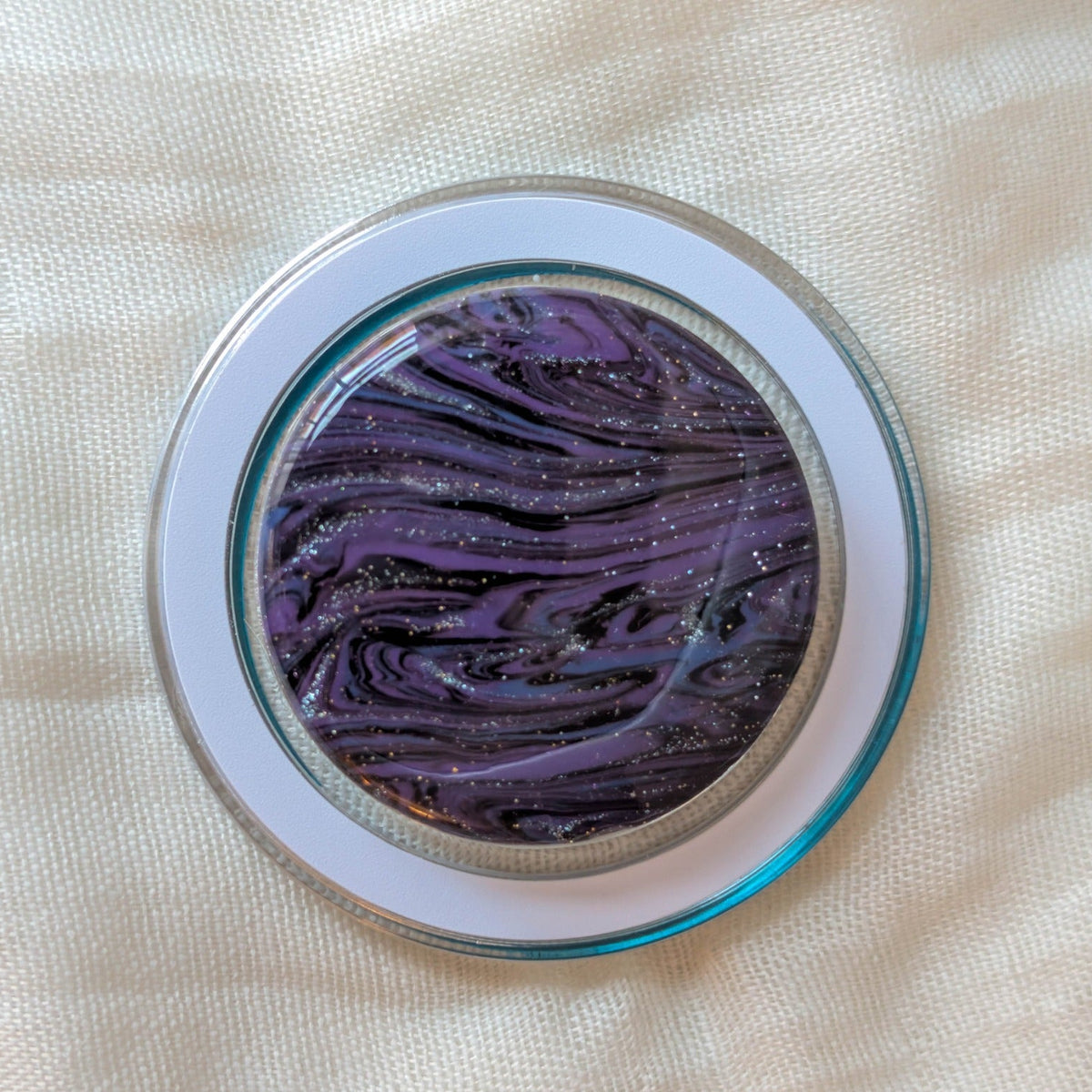 Close-up of clear MagSafe phone grip with purple black and blue handmade polymer clay marble under resin