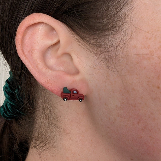 Mini red Christmas tree truck stud earring shown on ear for scale