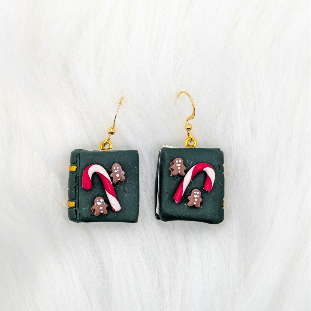 Green miniature book earrings decorated with candy canes and gingerbread people, with gold-tone hooks.