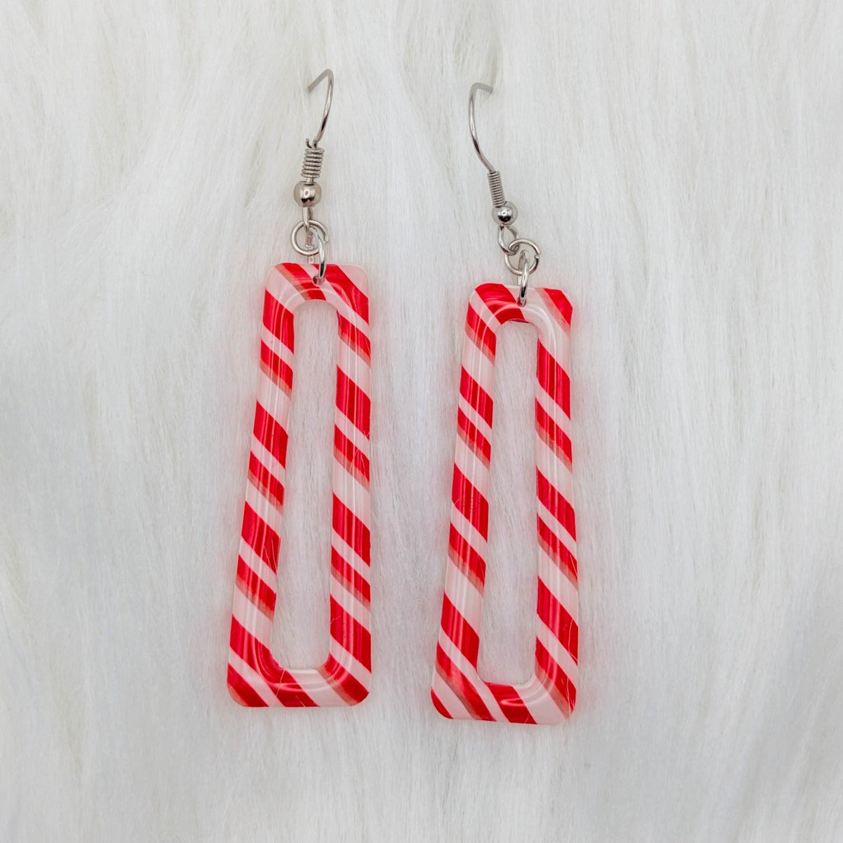 Long hollow candy cane striped dangle earrings in red, white, and translucent clay.