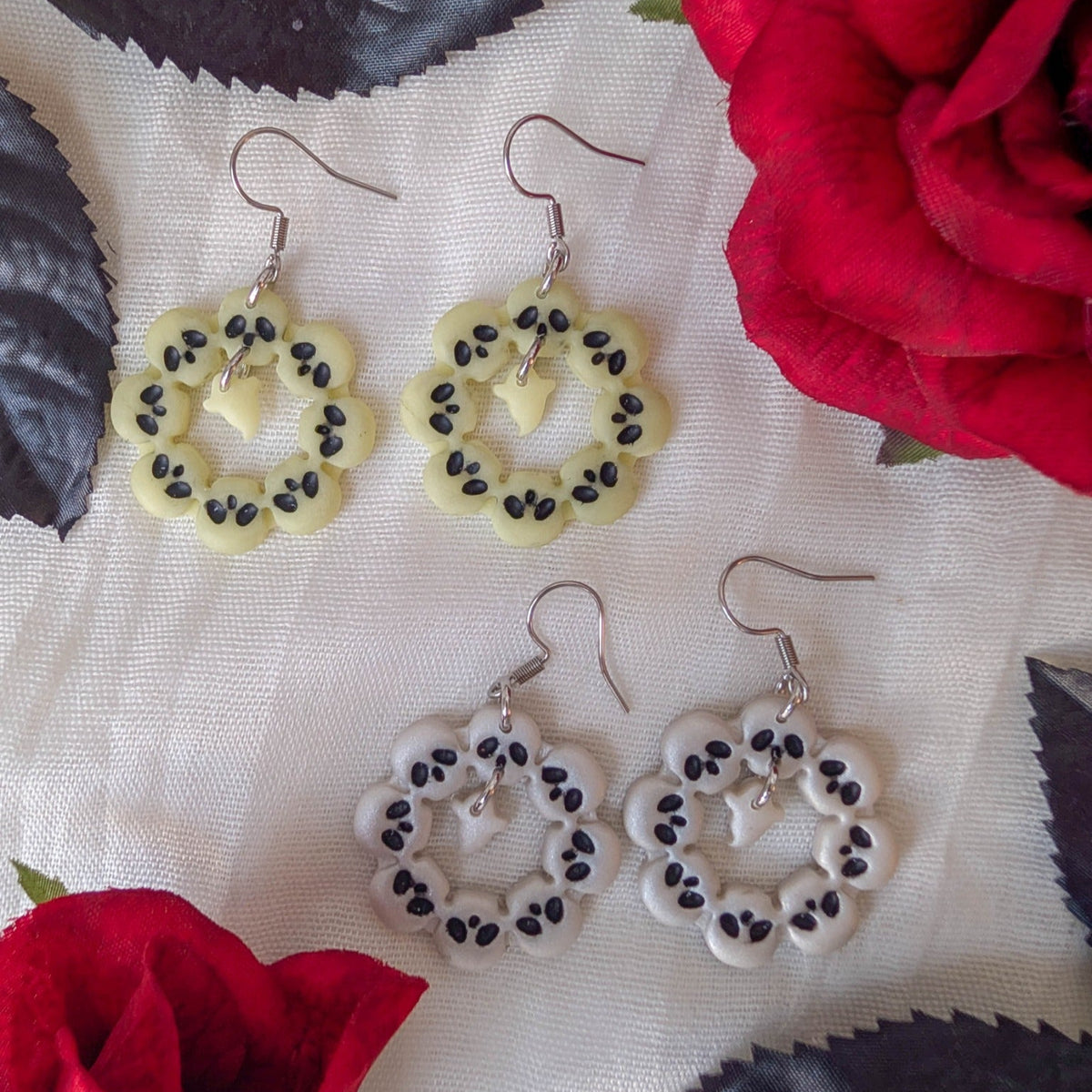 Pearl and glow-in-the-dark skull wreath ghost earrings styled with red roses and black leaves