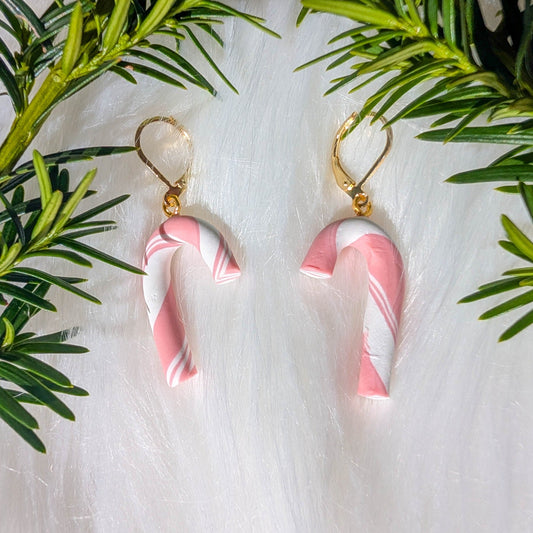 Pink and white hand-rolled candy cane earrings with gold-plated stainless steel findings styled with evergreen branches
