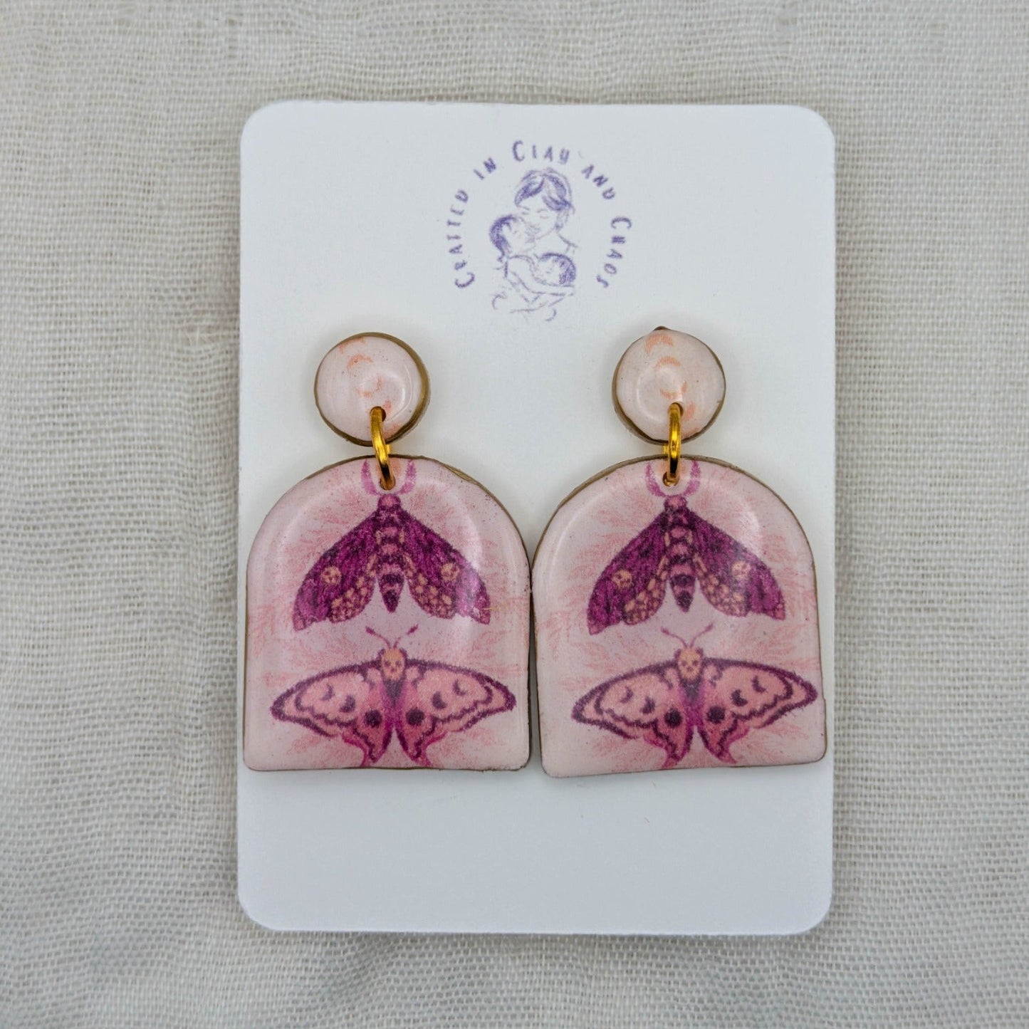 Pastel pink moth arch earrings with gold edging and celestial moth artwork