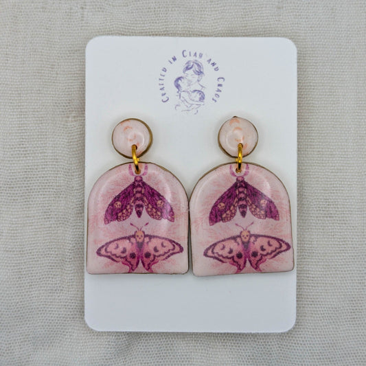 Pastel pink moth arch earrings with gold edging and celestial moth artwork