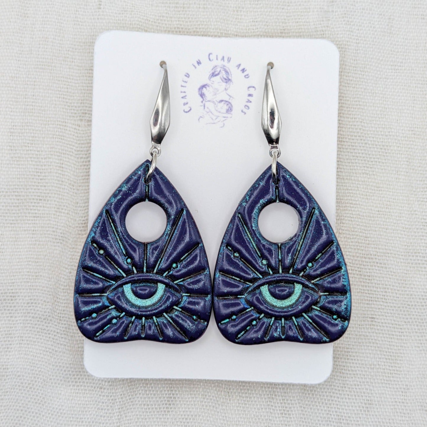 Purple galaxy shimmer planchette earrings with teal highlights, all-seeing eyes, and stainless steel hooks