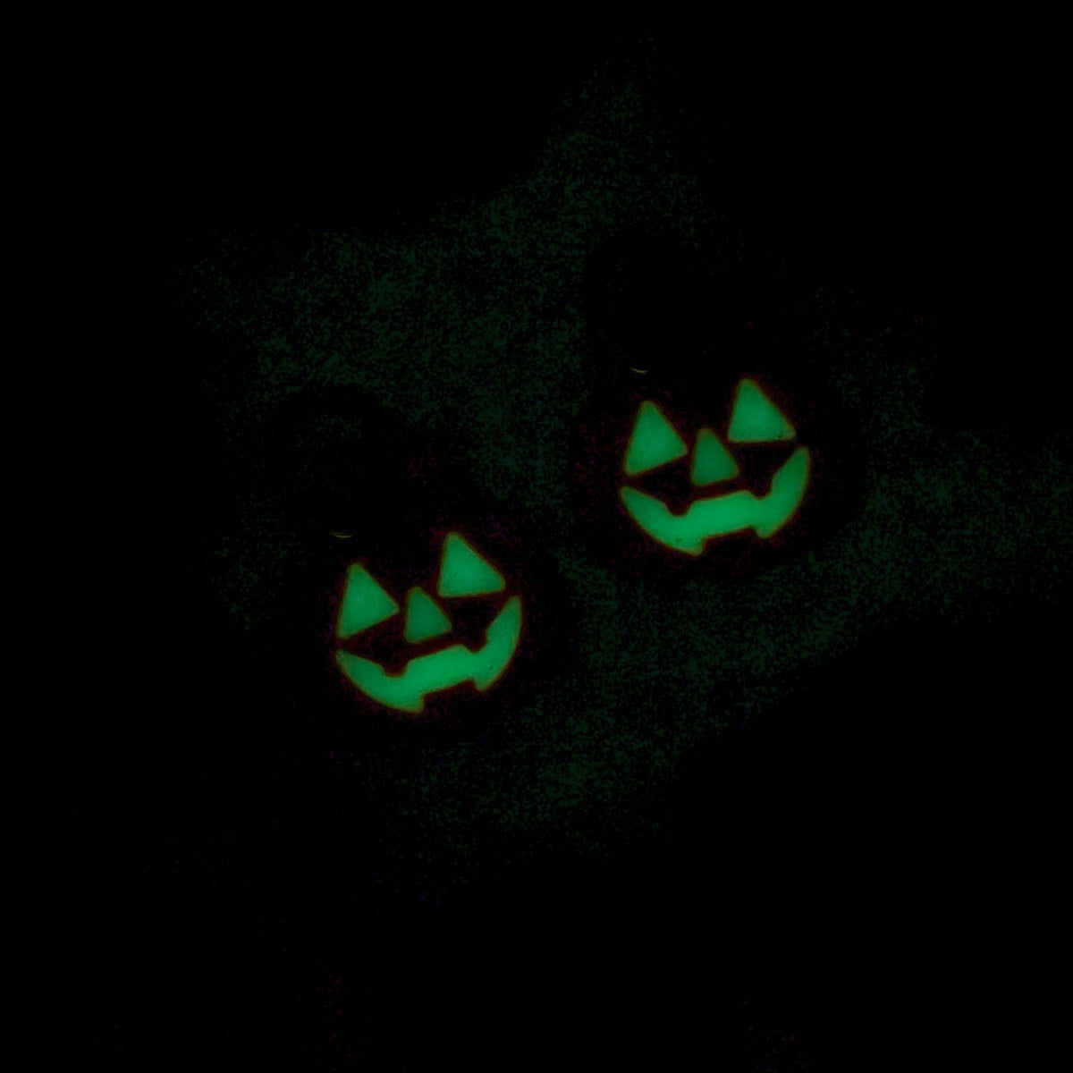 Jack-o-lantern faces glowing bright green in the dark on trick-or-treat pumpkin earrings