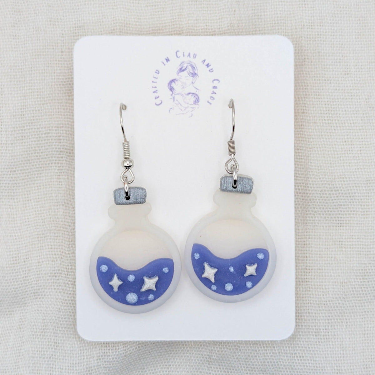 Purple translucent potion bottle earrings with painted white stars and bubbles on surgical-grade stainless steel hooks