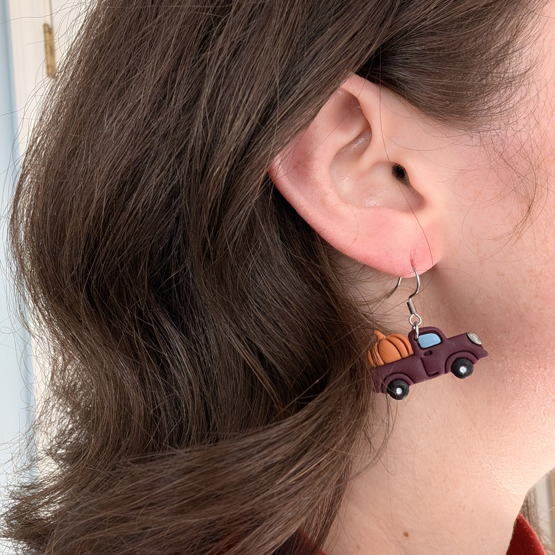 Burgundy vintage pumpkin truck earring with orange pumpkins worn on ear