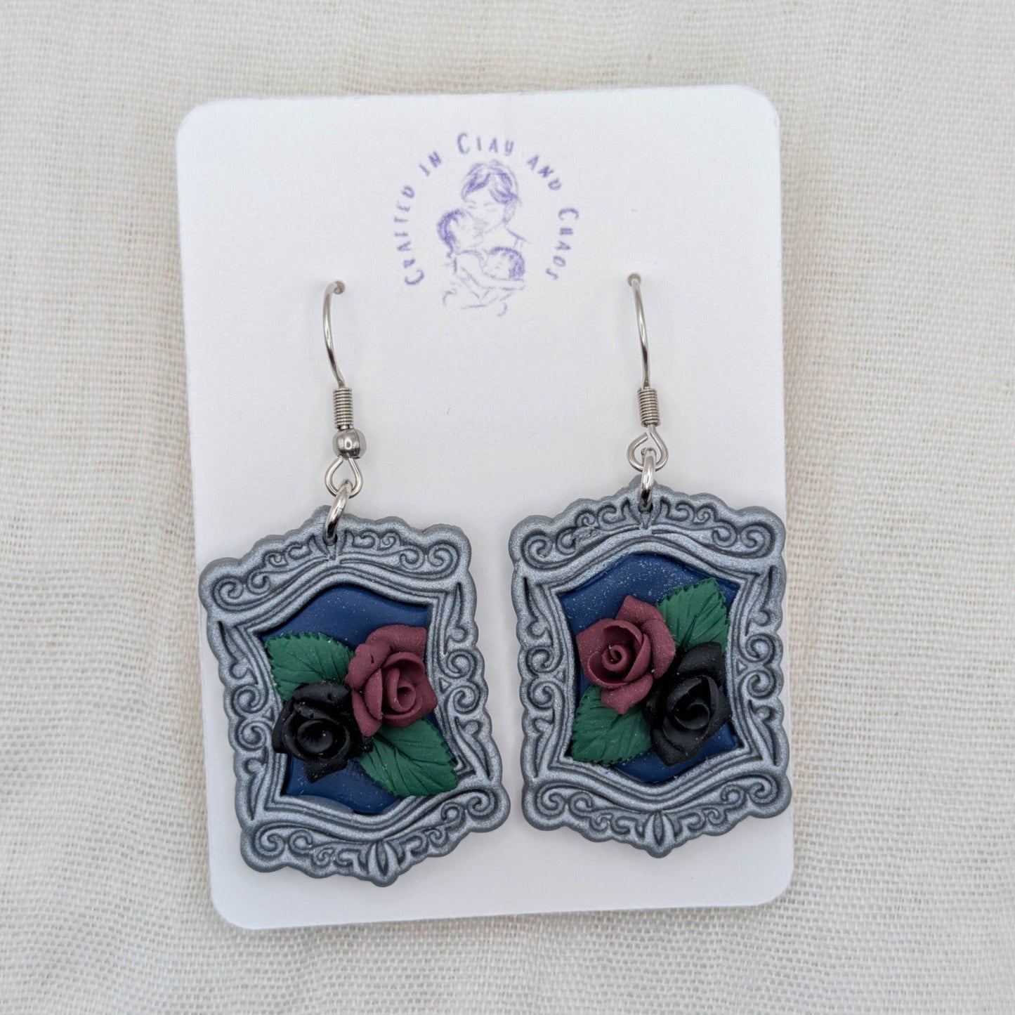 Silver vintage frame earrings with deep blue background, sculpted black and burgundy roses, and surgical-grade stainless steel hooks