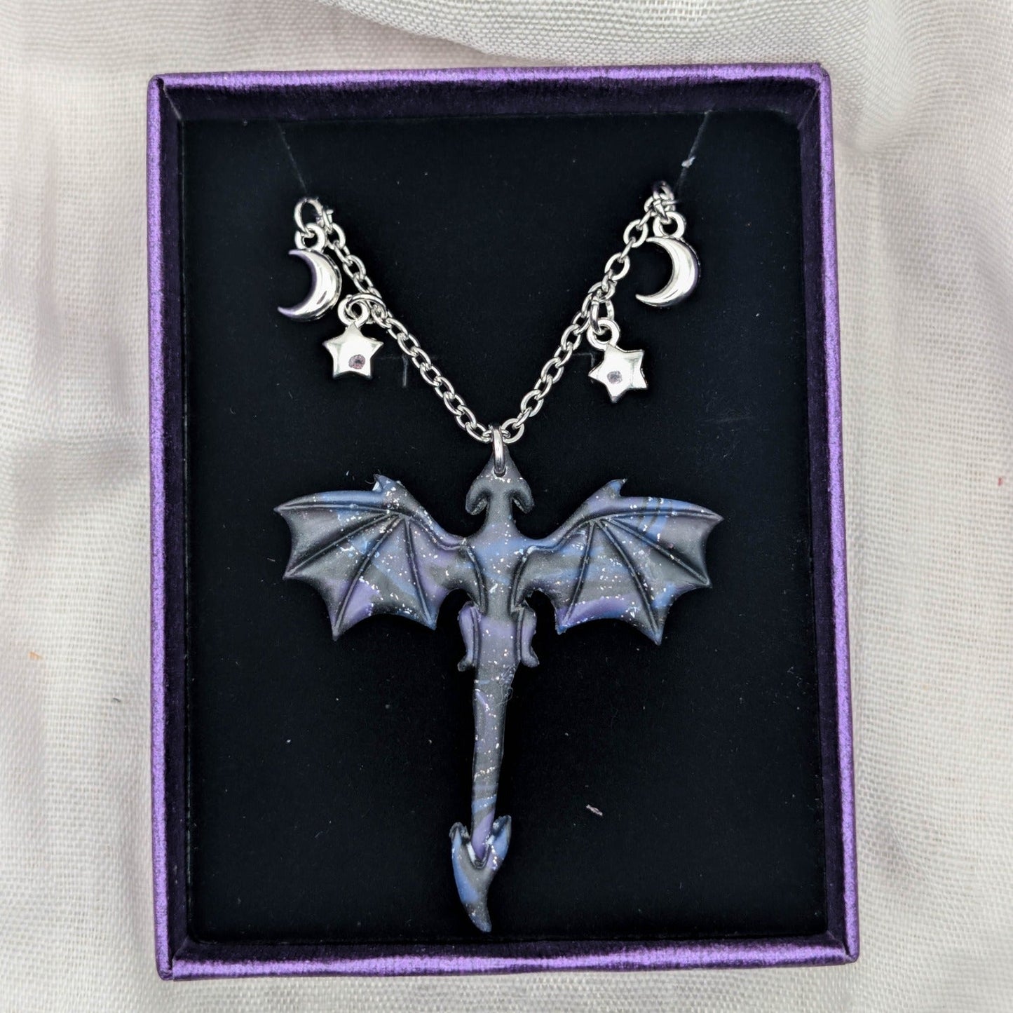 Silver-tone dragon necklace with marbled pendant and moon and star chain charms