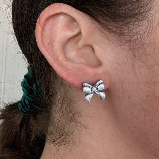 Silver foil crackle bow stud earring worn on ear to show its petite 2 cm size