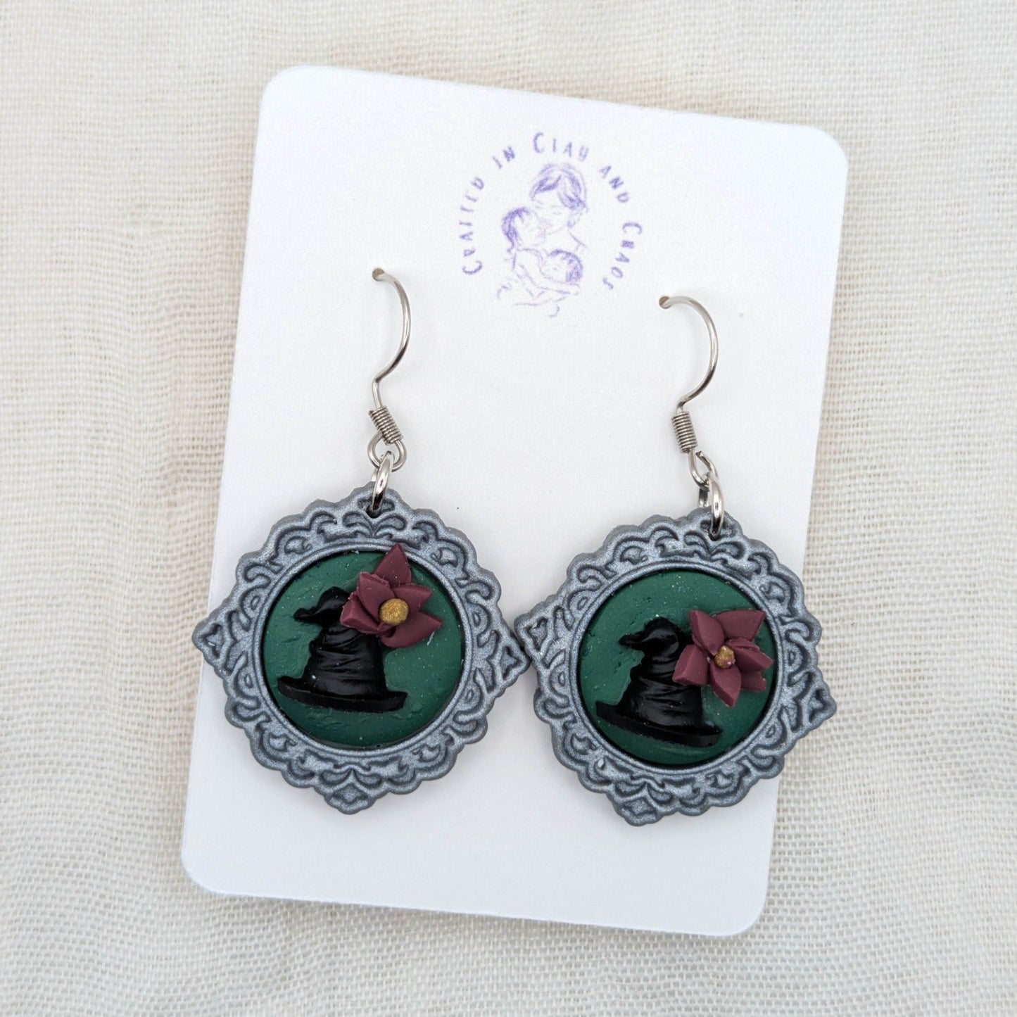 Silver round vintage frame earrings with green background, black witch hats, burgundy flowers, and surgical-grade stainless steel hooks