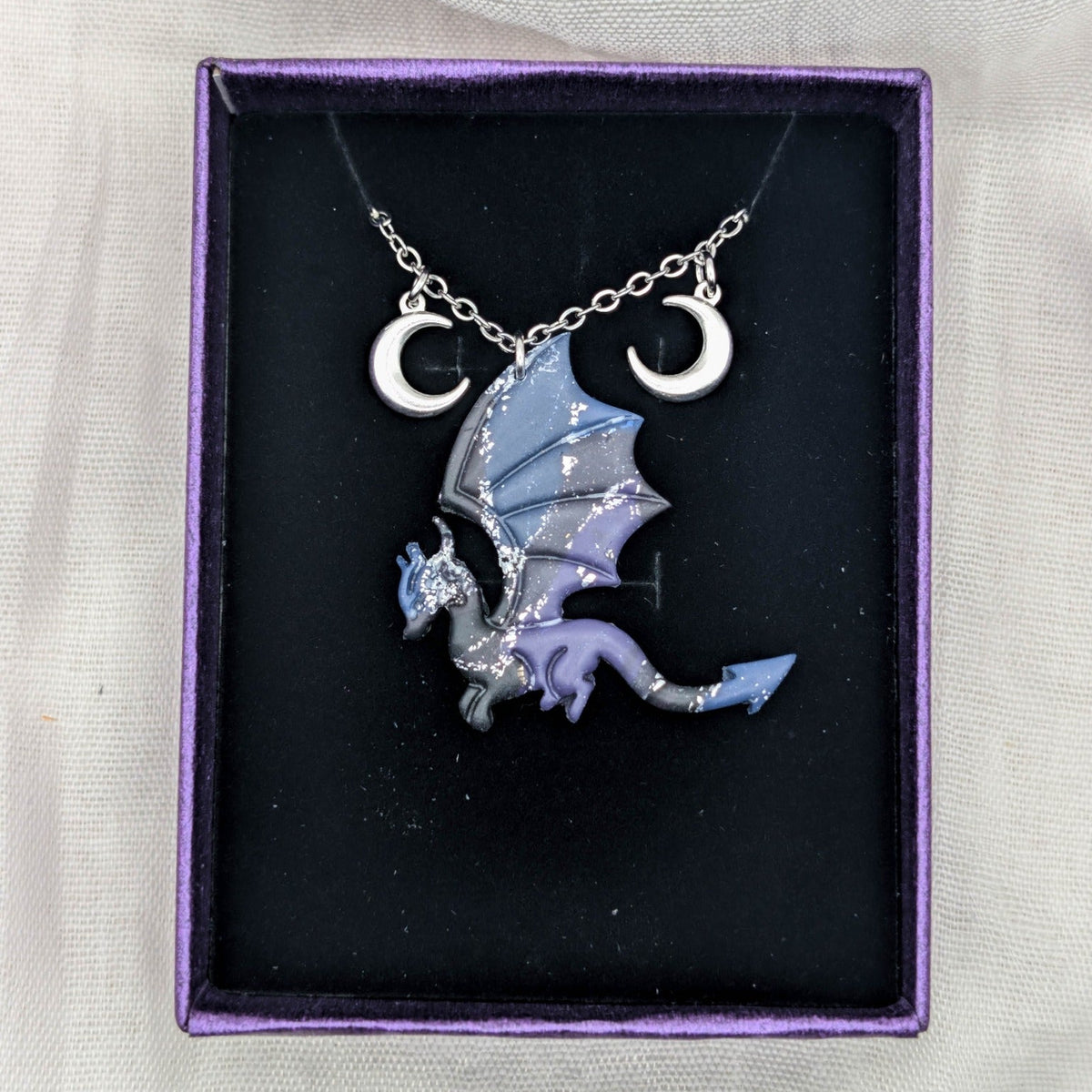 Side-profile fantasy dragon necklace with silver chain and two crescent moon charms