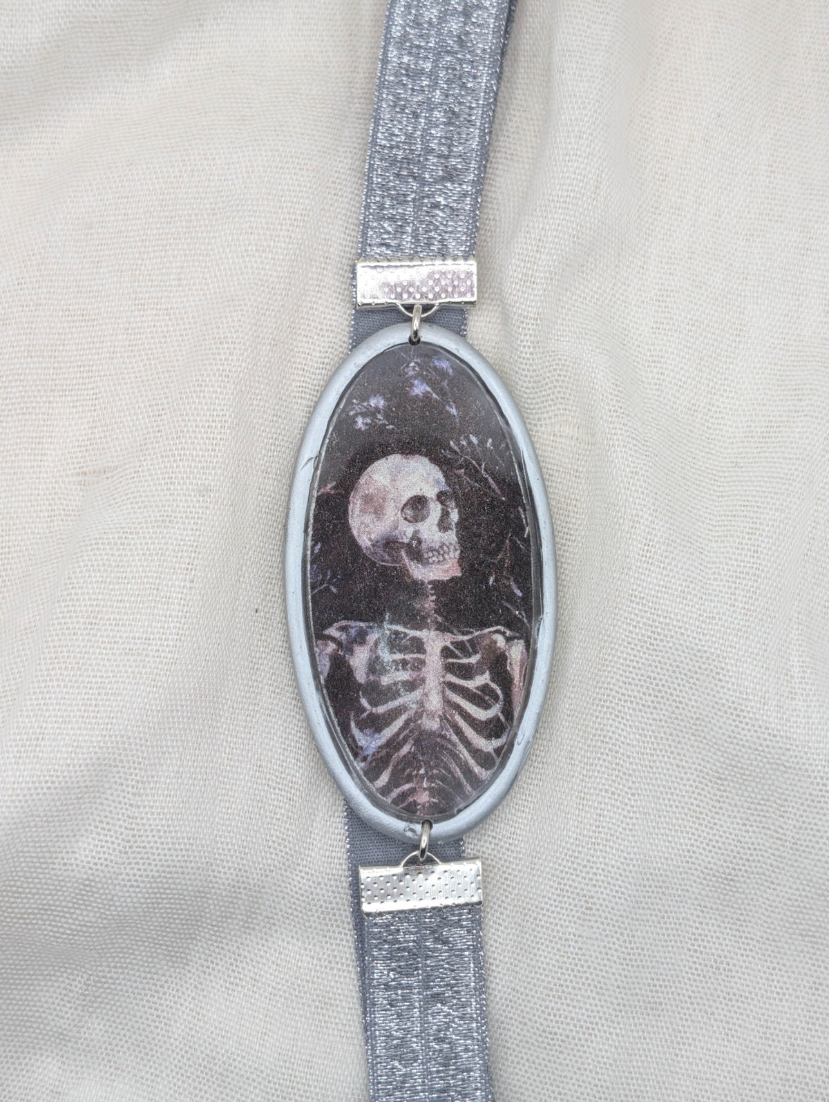 Silver framed gothic polymer clay wrap-around bookmark with a skeleton portrait and silver elastic band