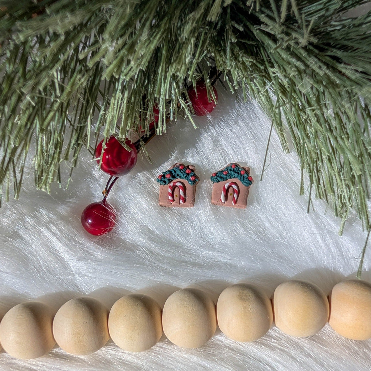 Traditional gingerbread house studs styled with evergreen branches, red berries, and wooden beads