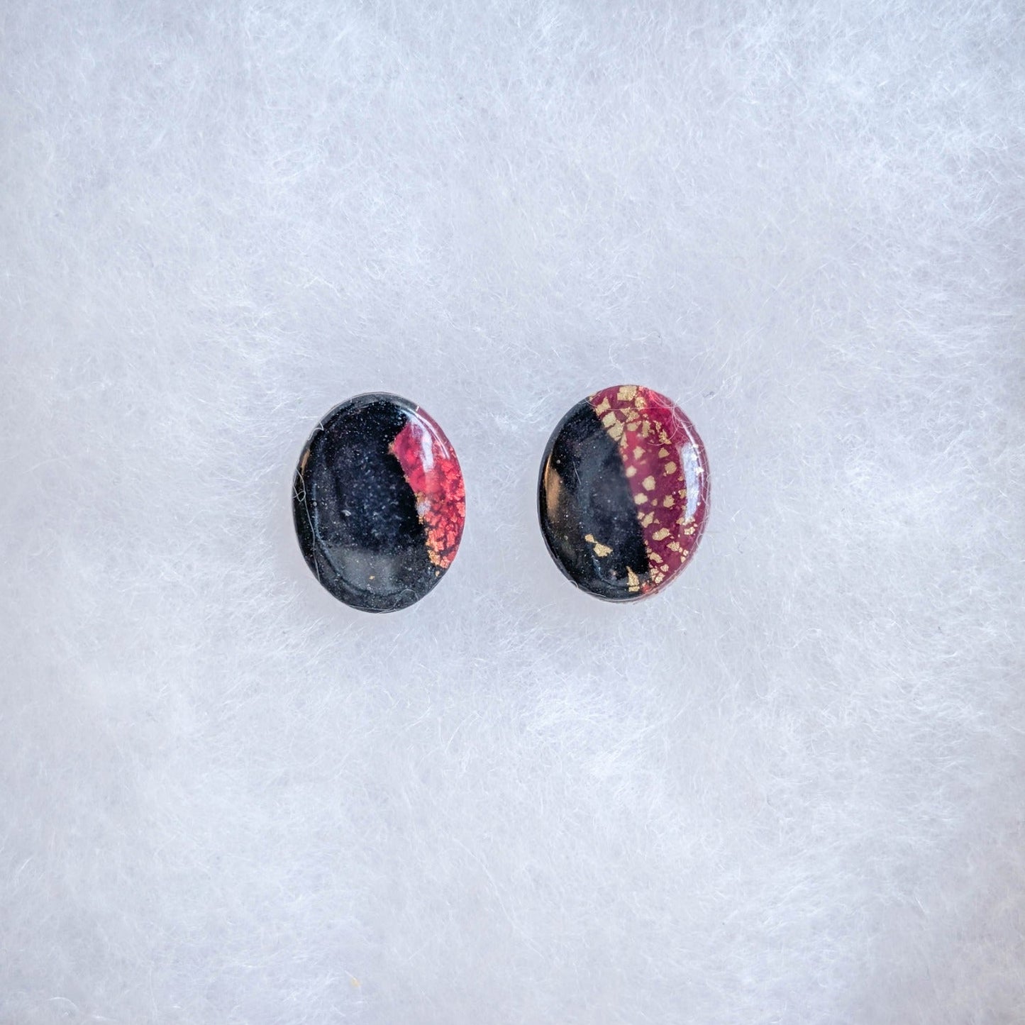 Translucent crimson and black oval stud earrings with gold streaks