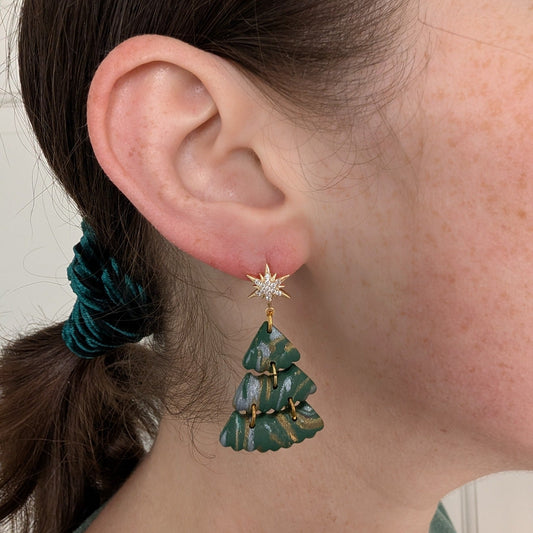 Green Christmas tree dangle earring with gold and silver swirls shown on ear