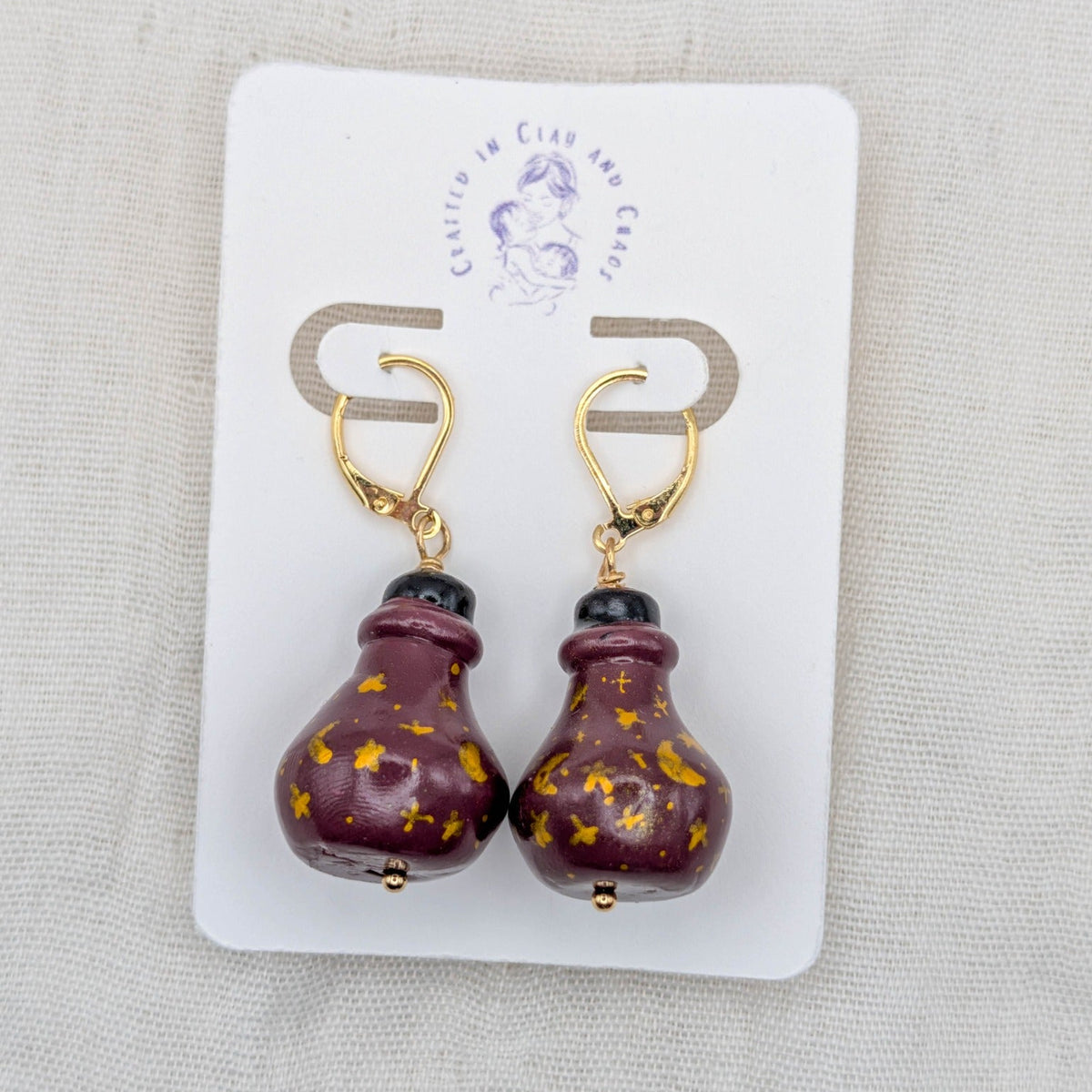 Wine red handmade 3D potion bottle earrings with hand-drawn gold celestial symbols and gold-plated leverbacks