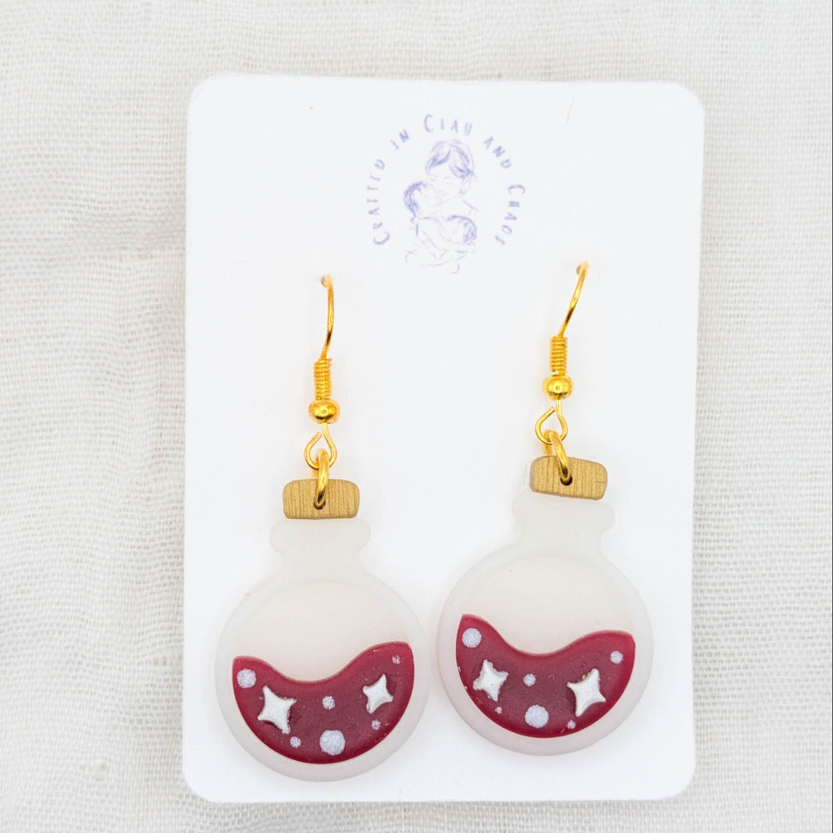 Wine red translucent potion bottle earrings with white stars and bubbles on 18K gold-plated stainless steel hooks