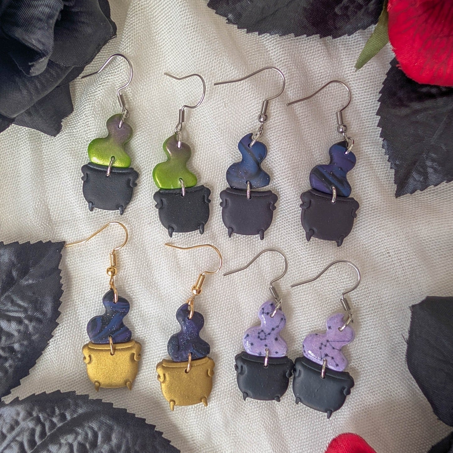 Five styles of witch cauldron polymer clay dangle earrings with colorful potion smoke, black, gray, purple, and gold cauldrons